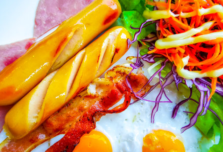 Intercontinental breakfast with sausages toast eggs salad bacon and a cup of coffee on a plate in a restaurant in Patong Beach Kathu District Phuket Island Province Southern Thailand.の写真素材