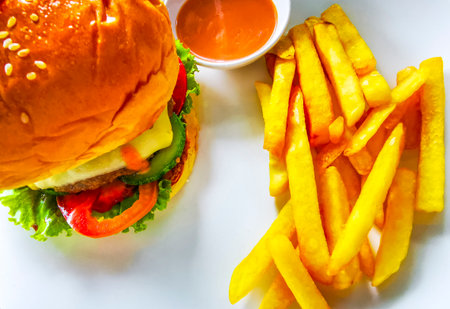 Crispy chicken or beef burger cheeseburger hamburger with golden yellow French fries on a plate in a restaurant in Patong Beach Kathu District Phuket Island Province Thailand.の写真素材