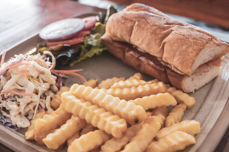 Salmon baguette sandwich with salad and French fries on a plate in a restaurant in Patong Beach Kathu District Phuket Island Province Southern Thailand in Southeast Asia.の写真素材