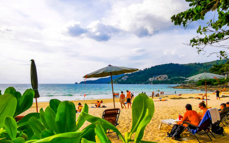 Kathu District Phuket Island Province Thailand December 17, 2025 Patong Beach bay with tourists people water waves sun loungers parasols tropical plants and palm trees in Phuket Thailand.のeditorial素材