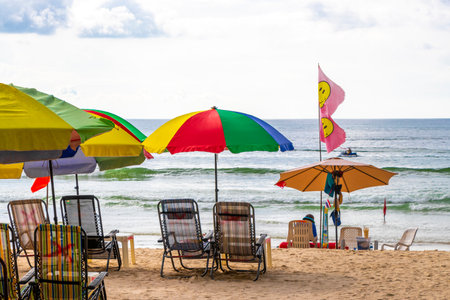Kathu District Phuket Island Province Thailand October 17, 2025 Patong Beach bay with tourists people water waves sun loungers parasols tropical plants and palm trees in Phuket Thailand.のeditorial素材