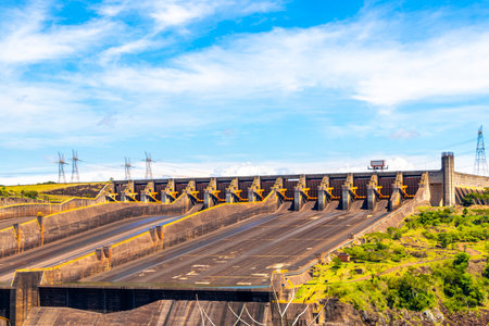 Brazil's largest dam in the world Itaipu for energy production on the border with Paraguay electricity pylons power poles building water river and blue sky in Foz do Iguacu State of Parana Brazil.の写真素材