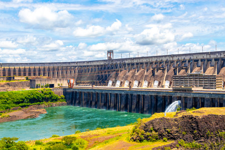 Brazil's largest dam in the world Itaipu for energy production on the border with Paraguay electricity pylons power poles building water river and blue sky in Foz do Iguacu State of Parana Brazil.の写真素材