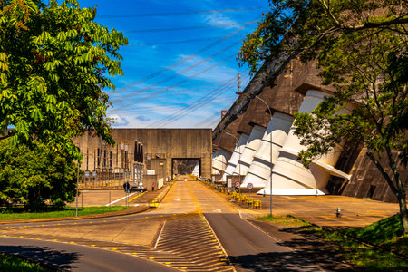Brazil's largest dam in the world Itaipu for energy production on the border with Paraguay electricity pylons power poles building water river and blue sky in Foz do Iguacu State of Parana Brazil.の写真素材