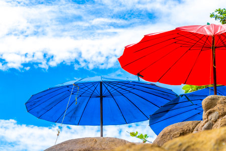 Patong Beach tourist bay with sun loungers parasols lounger parasol water waves blue sky rocks and tropical palm trees in Phuket Island Province Southern Thailand in Southeast Asia.の写真素材