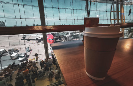 Thalang District Phuket Island Province Thailand December 29, 2025 Coffee to go take away cup mug on the wooden table at the international airport airplane plane with beach panorama view in Thailand.のeditorial素材