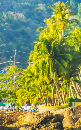 Kathu District Phuket Island Province Thailand February 04, 2026 Amazing rocky Kalim Beach tropical landscape panorama view with blue sky turquoise water waves palm trees rocks Patong Beach Thailand.の写真素材