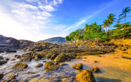 Rocky tropical seascape shore coast with turquoise blue green clear water waves sand boulders stones and rocks.の写真素材