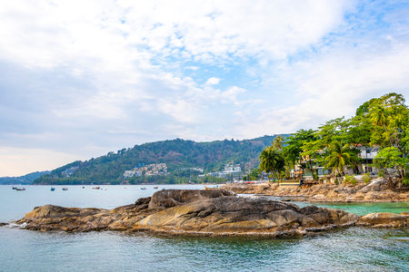 Amazing rocky Kalim Beach tropical landscape panorama view with blue sky turquoise water waves palm trees and rocks in Patong Beach Kathu Phuket Island Province Southern Thailand in Southeast Asia.の写真素材
