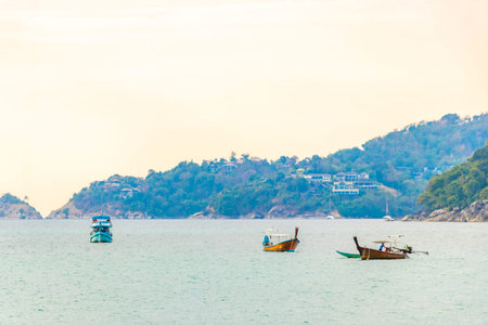 Longtail boat long tail boats with clear blue turquoise water rocks tropical palm tress and sky shore coast seascape panorama view in Patong Beach Phuket Island Thailand.の写真素材