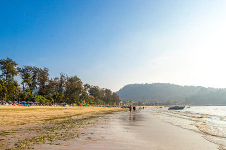 Kathu District Phuket Island Province Thailand 05. March 2026 Patong Kamala Beach bay with tourists people water waves sun loungers parasols tropical plants blue sky and palm trees in Phuket Thailand.のeditorial素材