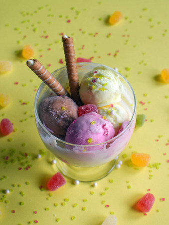 A cup of ice cream with rolled wafers. ice cream closeup, with yellow background.の写真素材