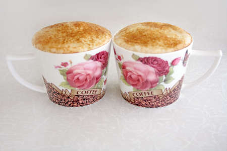 Two cups of coffee with foam stand on the tableの写真素材
