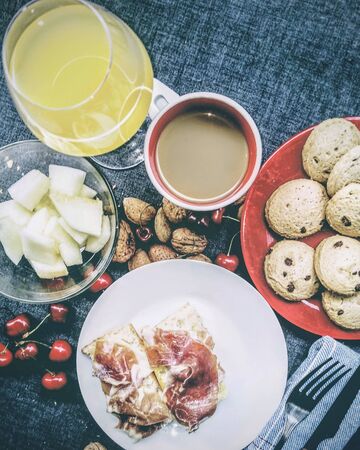 Full breakfast with melon, ham, cherry, walnut toast, chocolate pastes, orange juice and coffee. On a blue tableclothの写真素材