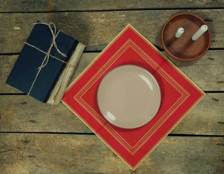 plate on wooden table near candels and aged booksの写真素材