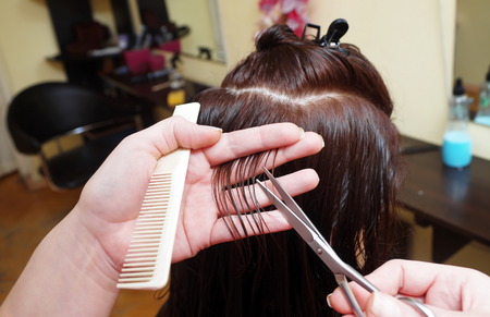hairdresser is doing a haircut for customer in a salon closepの写真素材