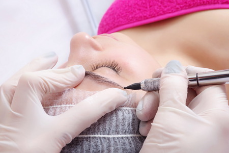 tattooist is using  gun tool for eyebrows tattoo closeupの写真素材