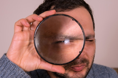Man is looking through a big magnifier closeupの写真素材