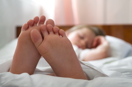 little girl's feet who sleeps inher bed closeupの写真素材