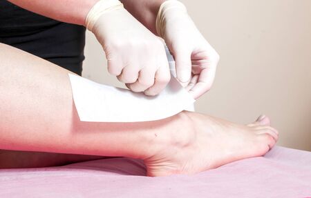 a beauty therapist is waxing client's legsの写真素材
