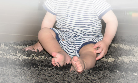toddler foot who  sits on a rug の写真素材