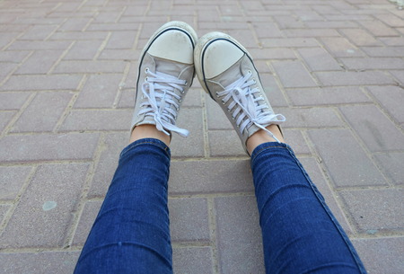 girl's legs in sport shjes and jins lay on groundの写真素材