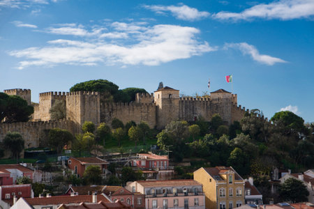 A scenic view of the medieval Sao Jorge Castle (Castelo de Sao Jorge) perched atop the highest hill in Lisbon, Portugal, seen from the narrow streets of the downtown areaの写真素材