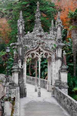 A highly ornate, neo-Gothic style stone archway and bridge in the lush, green gardens of Quinta da Regaleira in Sintra, Portugalの写真素材
