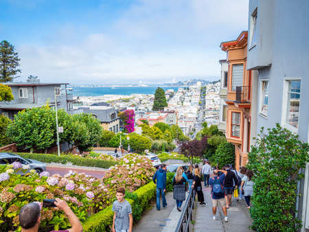 San Francisco, US, Aug 2019: Lombard Street, east west street in San Francisco, California famous for a steep, one block section with eight hairpin turns. Victorian houses and bay in the background.のeditorial素材