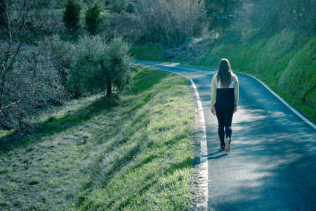 Blonde curvy and beautiful girl walks in the beauty of the Tuscan hills and olive grove and trees. Nature, relaxation, history, culture and good food for an unforgettable holiday.の写真素材