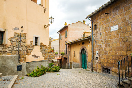 The charming Via del Corso in Tuscania, Italy, showcases a picturesque scene of old buildings with weathered facades and cobblestone paving, creating a timeless atmosphere in this historic townの写真素材