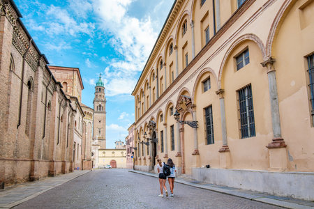 Three young women tourists walking in Piazza Duomo in Parma, near the Duomo and Baptistery, enjoying a sunny summer day while admiring the ancient architectureの写真素材