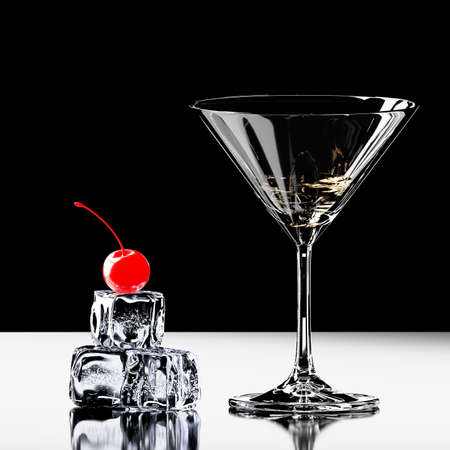 A glass of martini on the table. Nearby are ice cubes, top cherries in syrup. 3D visualizationの写真素材
