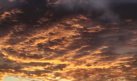 Dramatic golden cloudy sky. Sun rays through the dark cloudsの写真素材