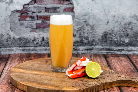 A glass beer sitting on top of a wooden tableの写真素材