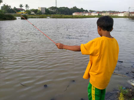 Cibitung, Bekasi, Indonesia - June 19, 2020 : children fishing in a pondのeditorial素材