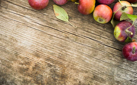 Fresh red apples with green leaves on wooden table. On wooden background. Free space for text. Top viewの写真素材
