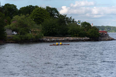 A man rowing on a small boat in the middle of the lake.