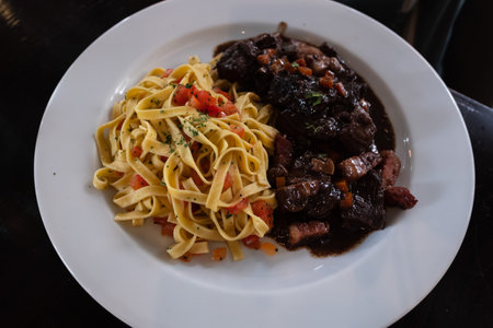 Linguine pasta with beef and vegetables on a white plate.