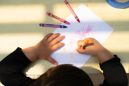 little girl drawing with crayons on paper.topviewの写真素材