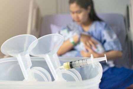 Mother holding a baby syringe with breast milk for breastfeeding at foreground, mothers breast milk is the most healthy food for newborn baby.の写真素材