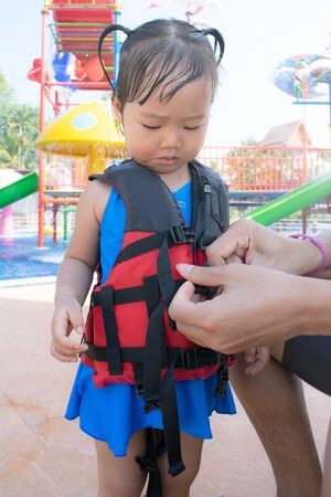 A father helping his daughter with her life jacket.の写真素材