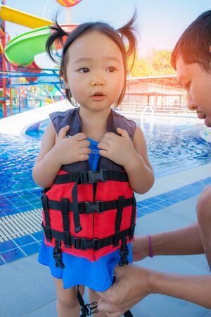A father helping his daughter with her life jacket.の写真素材
