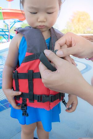 A father helping his daughter with her life jacket.の写真素材