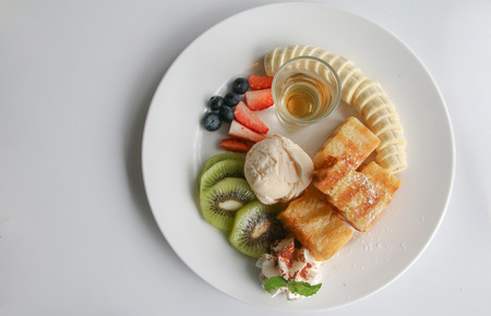 Bread topped with honey, vanilla ice cream Supplement with Banana and Kiwi White backgroundの写真素材