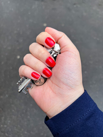 A female hand with red manicure clutching the apartment keys
