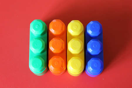 Pieces of plastic rainbow multicolored buildable toy blocks formed and arranged on red background