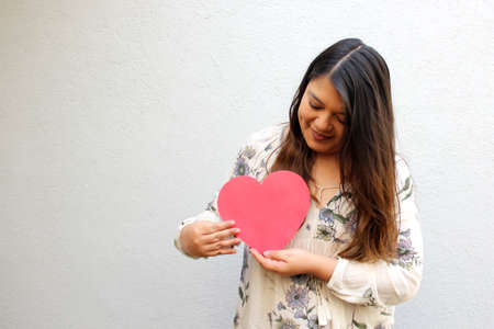 Latin adult woman shows her enthusiasm for the arrival of February and celebrate Valentine's Day of Love and Friendship with love and affection to give to her family, partner, friendsの写真素材