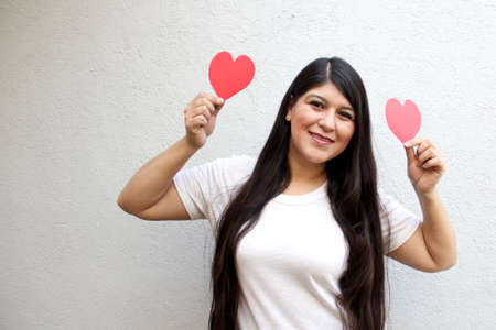 Latin adult woman shows her enthusiasm for the arrival of February and celebrate Valentine's Day of Love and Friendship with love and affection by givingの写真素材