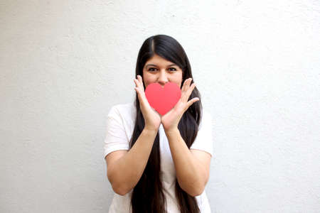 Latin adult woman shows her enthusiasm for the arrival of February and celebrate Valentine's Day of Love and Friendship with love and affection by givingの写真素材
